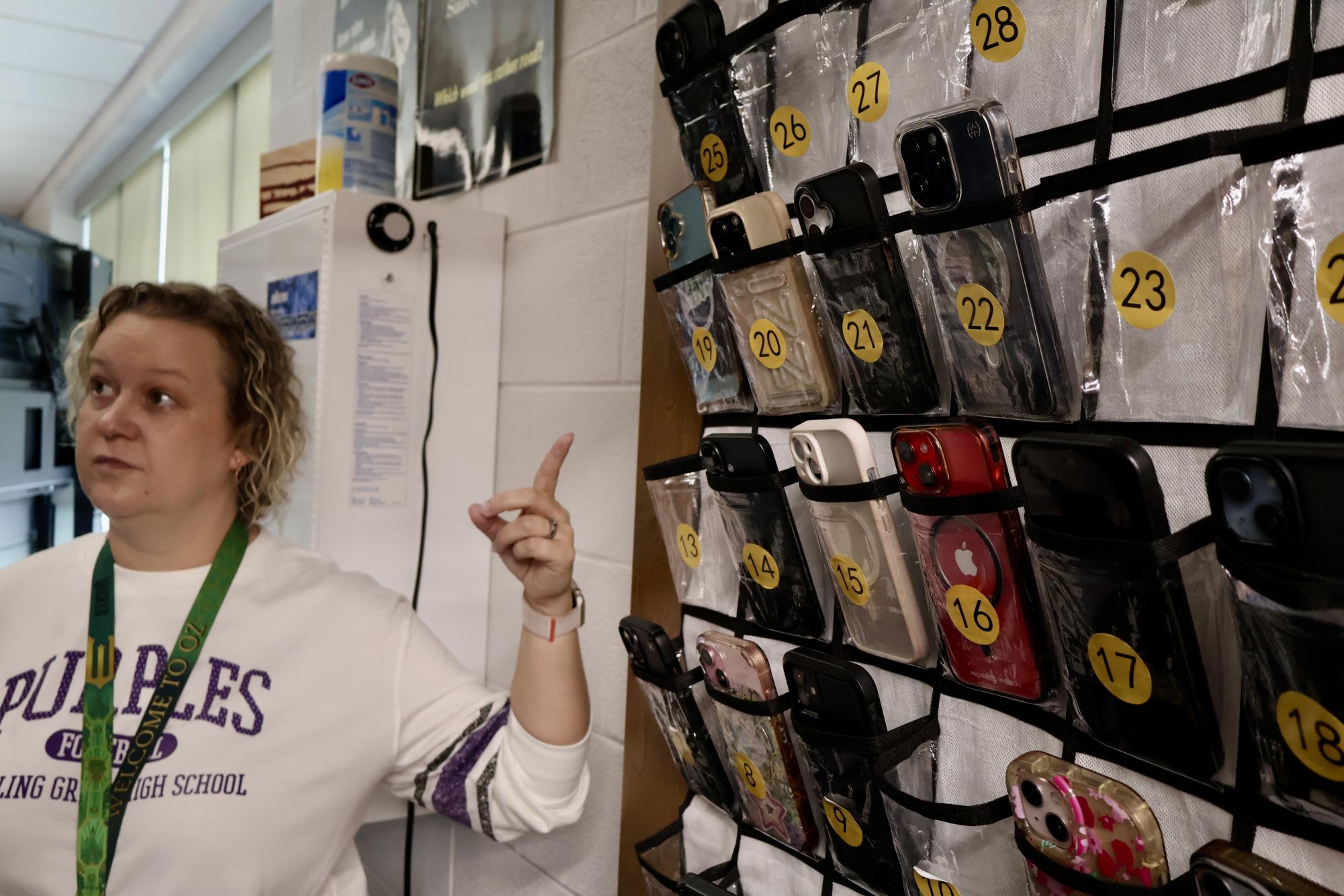 Chemistry teacher Marti Watson stands in front of the phone pouches she uses to enforce the new phone rule.